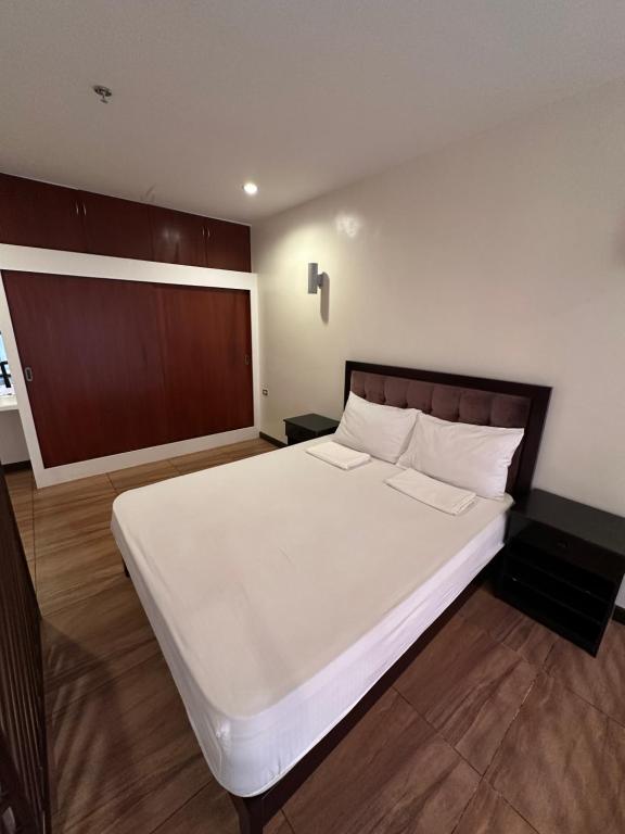 a bedroom with a large white bed with a wooden headboard at Uptown Condotel in Bulwa
