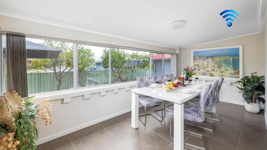 a dining room with a table and chairs and windows at Shoal Sanctuary in Nelson Bay