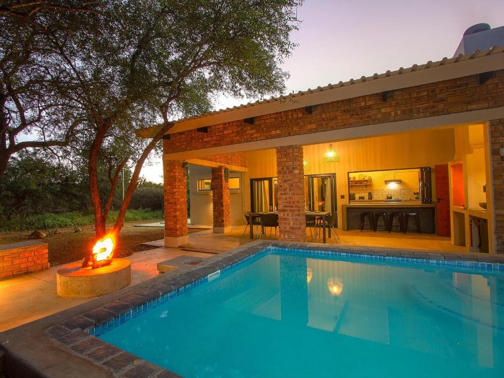a swimming pool with a fire in front of a house at Spoorzicht in Marloth Park