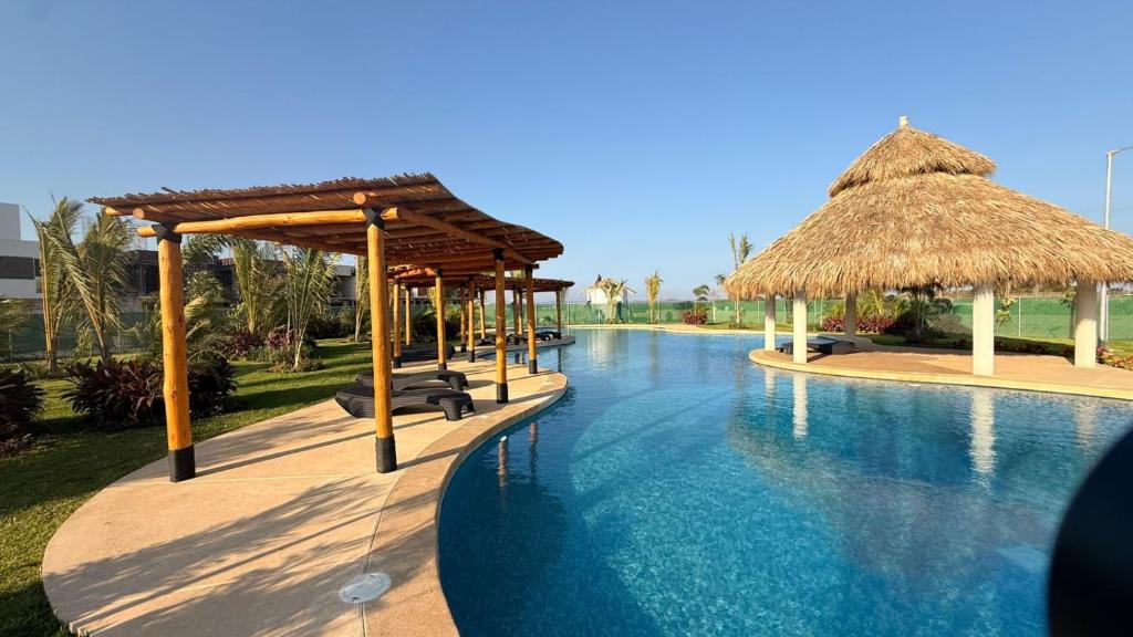 a resort with a swimming pool with thatched umbrellas at BellitasHouse Dream Acapulco Lujo y Confort in Acapulco