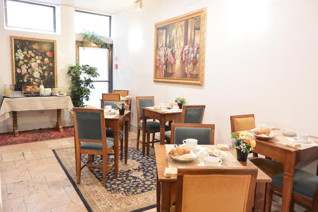 a dining room with tables and chairs and a painting on the wall at Hotel San Zulian in Venice