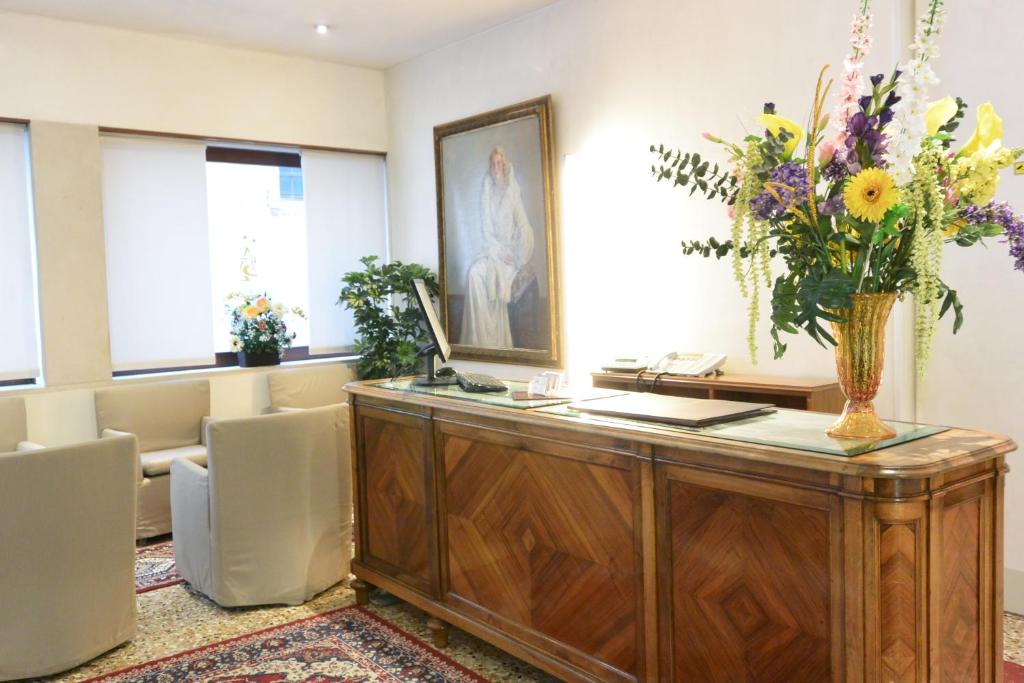 a waiting room with a desk with a vase of flowers at Hotel San Zulian in Venice