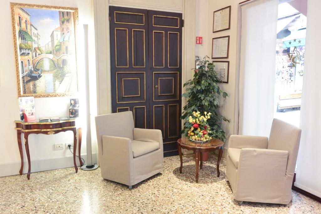 a lobby with a christmas tree and two chairs and a door at Hotel San Zulian in Venice