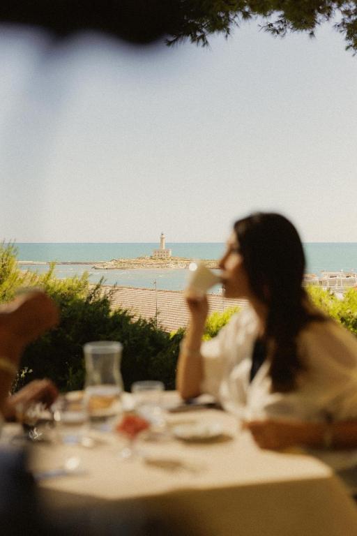a woman sitting at a table drinking a cup of coffee at Dimora Cummà Marì in Vieste