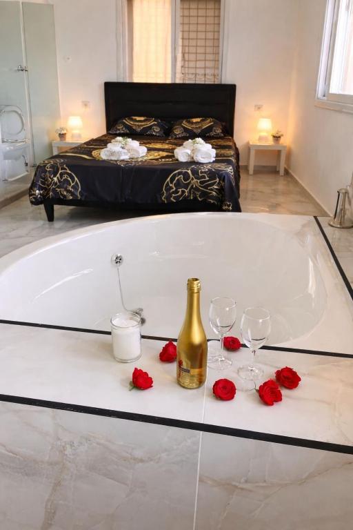 a bath tub with two wine glasses and red roses at Romy secrets in Netanya