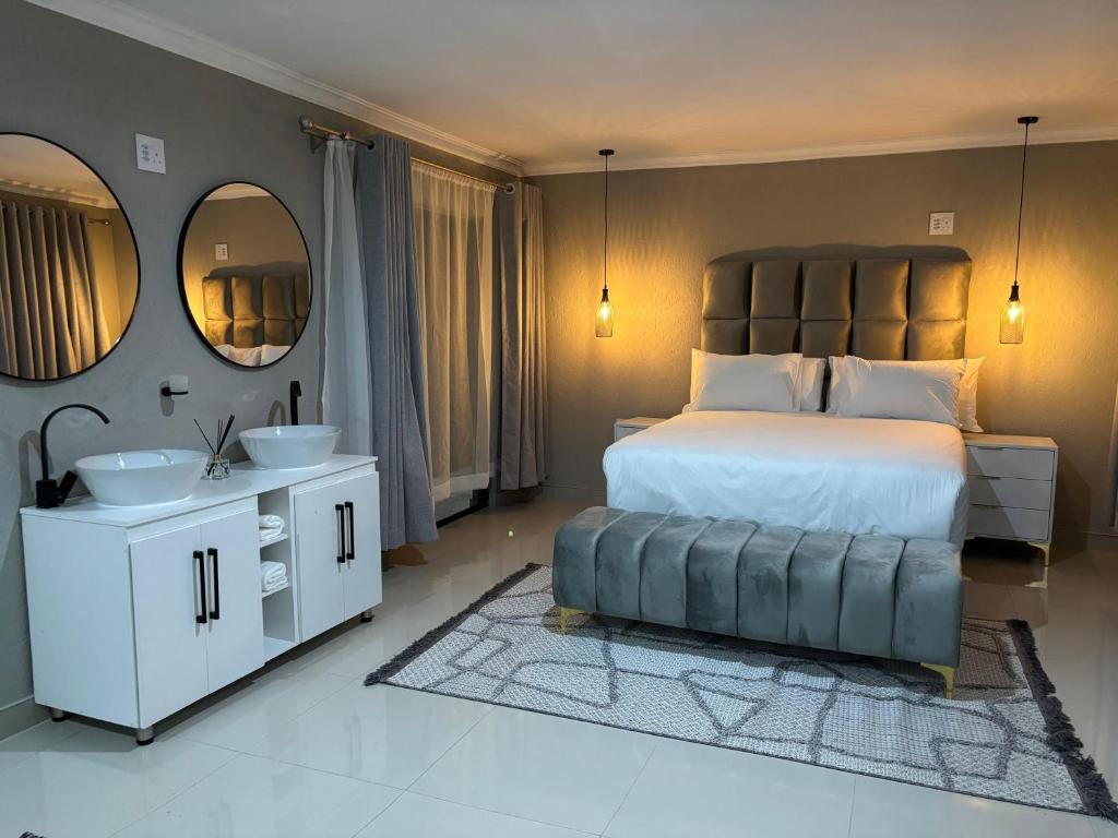 a bedroom with a bed and a sink and mirrors at Amahle Guesthouse Bush in Dwarsloop