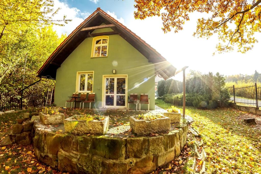 a small green house with a stone circle in front of it at Dom Maciejówka in Polanica-Zdrój