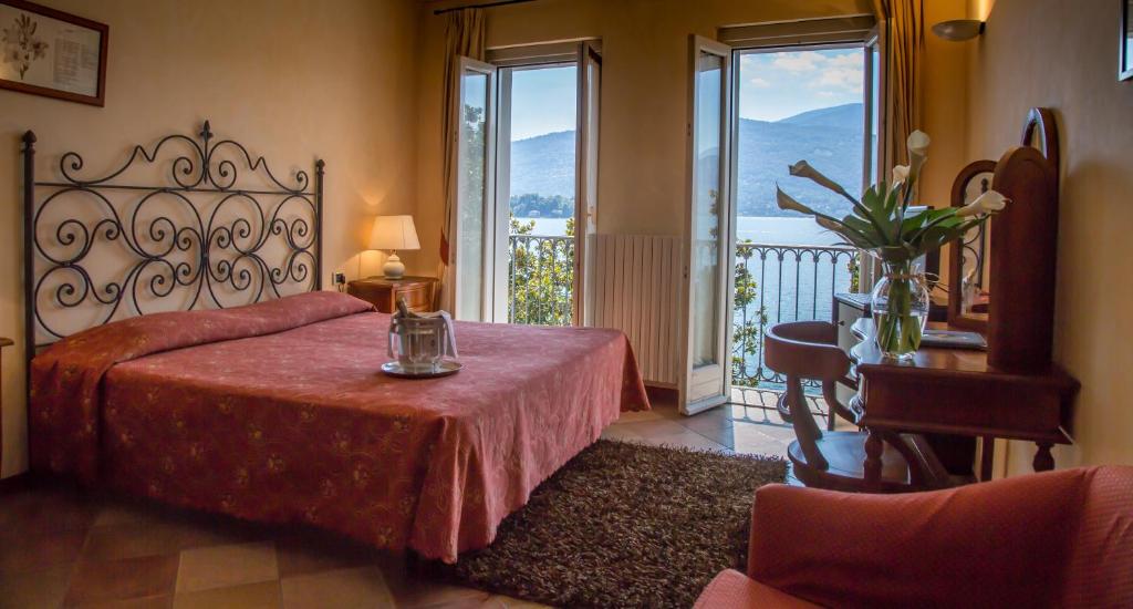 a bedroom with a bed with a table and windows at Hotel Aquadolce in Verbania