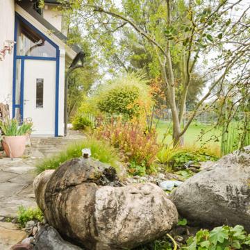a garden with rocks and a house and a tree at Kleine Bella in Ilmmünster