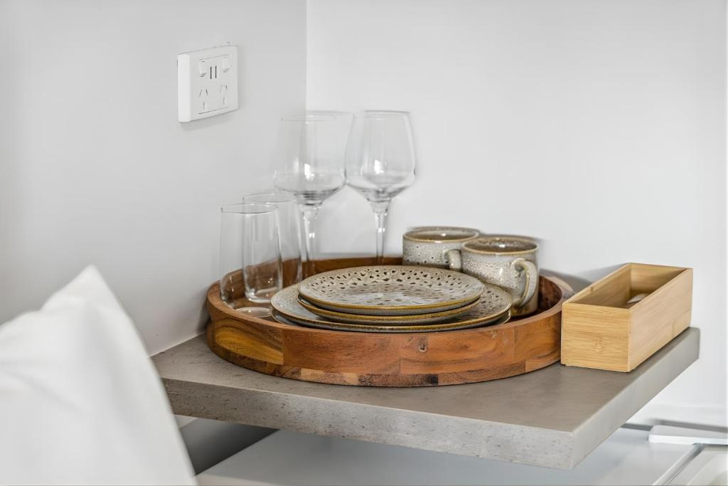 a tray with plates and wine glasses on a shelf at Darwin CBD Escape-Cosy and Central in Darwin