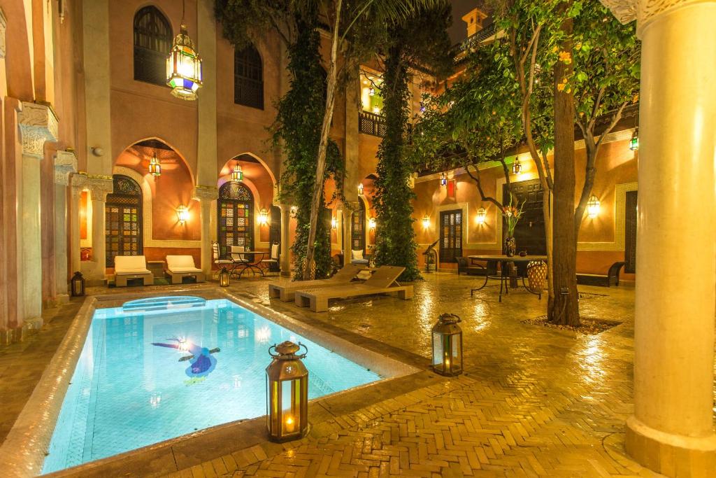 
a large swimming pool with a large fountain in the middle of it at Riad Le Perroquet Bleu Suites & Spa in Marrakech
