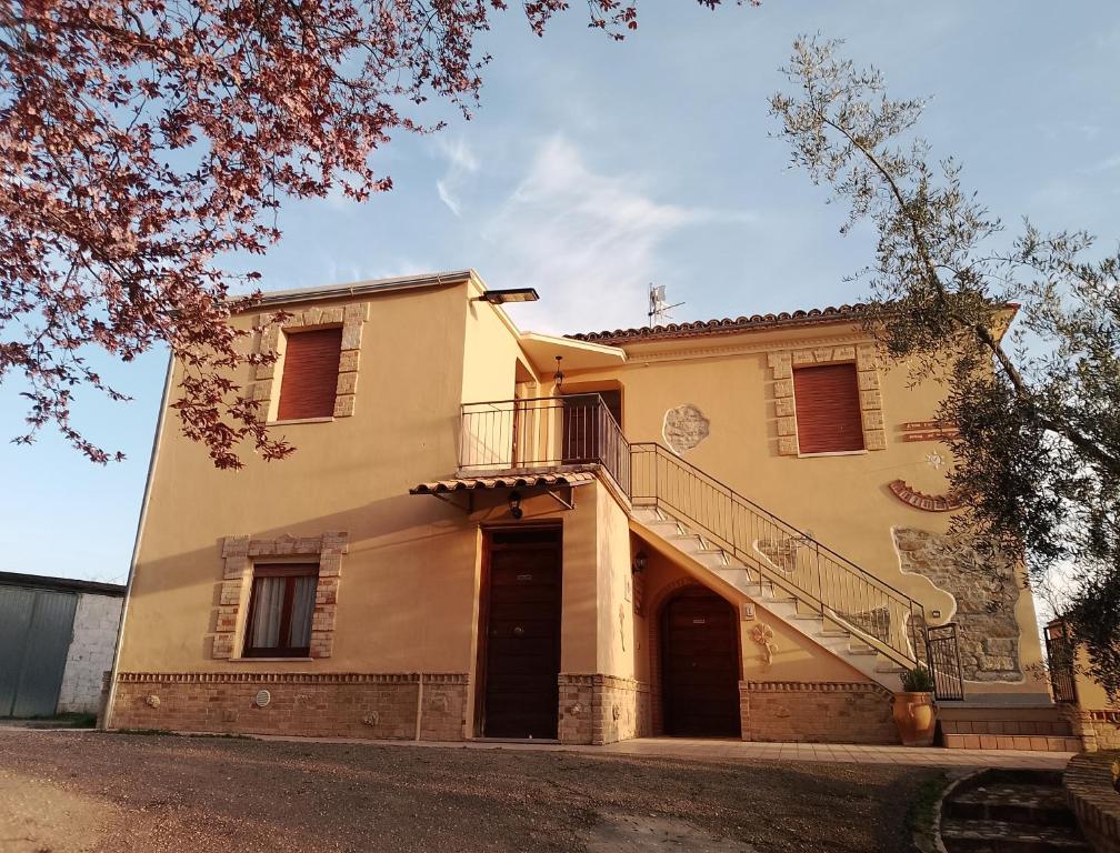 a large yellow house with a staircase on it at La Vecchia Fontana in Penne