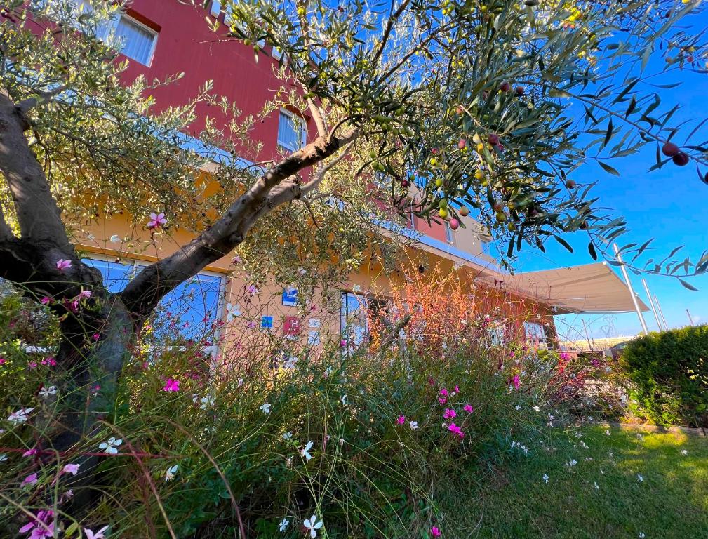 ein Gebäude mit einem Baum und Blumen davor in der Unterkunft The Originals City, Hôtel Ecoparc, Montpellier Est in Saint-Aunès