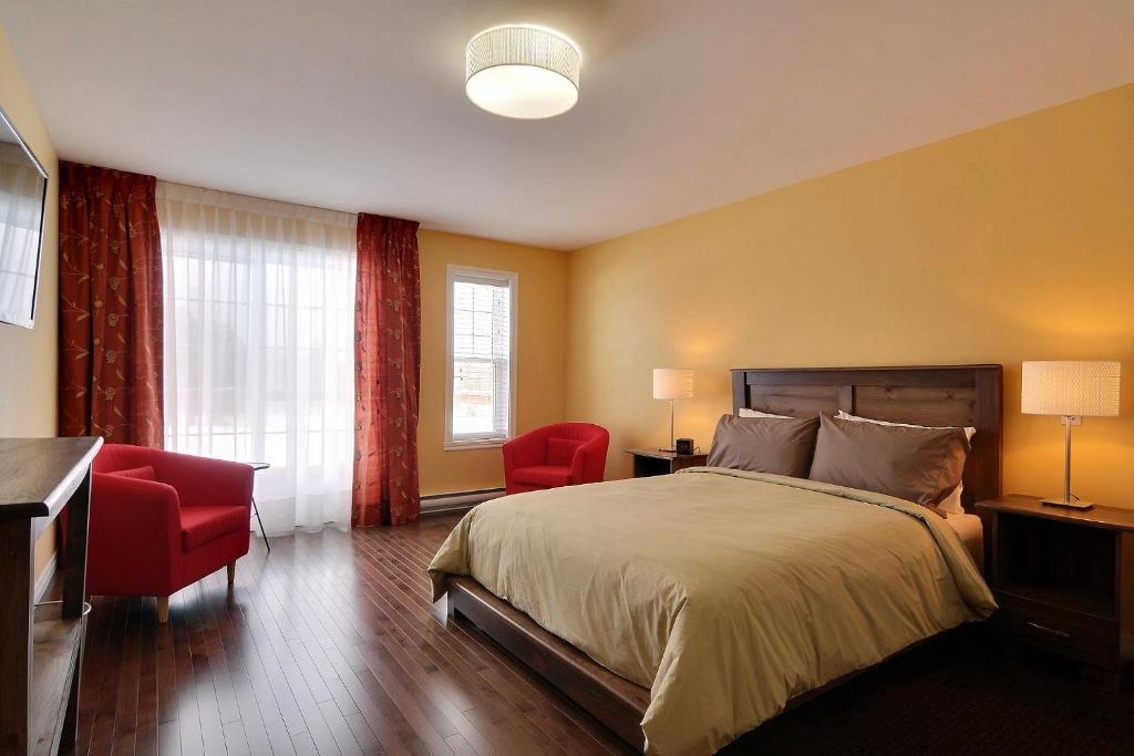 a bedroom with a bed and two red chairs at Gî'Temps couette et café B&B in Granby