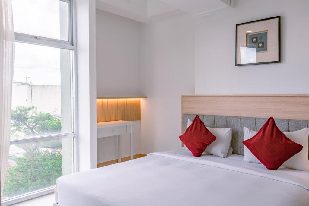 a bedroom with a large white bed with red pillows at Orbit House in Bandung