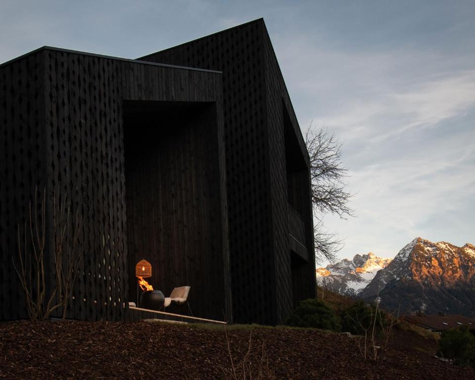 a black building with a person sitting in the doorway at Anton & Cilli Hideaway Lodges in Obermaiselstein