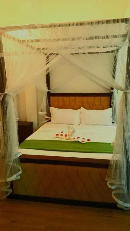 a bedroom with a canopy bed with red flowers on it at THARUMINI villa in Kandy