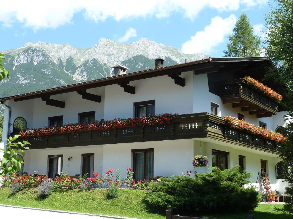 a building with a balcony and mountains in the background at Pension Holzmann in Leutasch