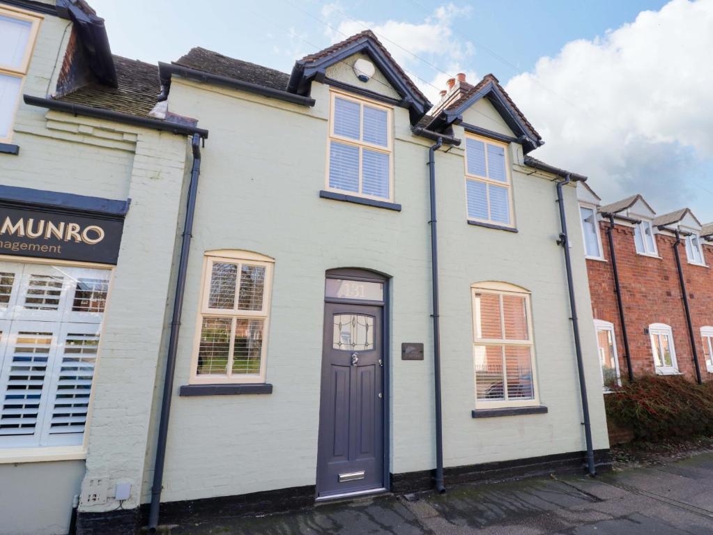a white house with a black door on a street at Fern Cottage in Lichfield