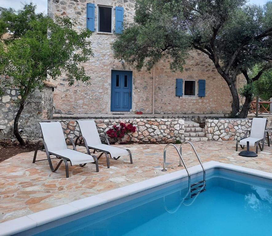 a swimming pool with two chairs and a building at Mathilda's House in Tselendáta
