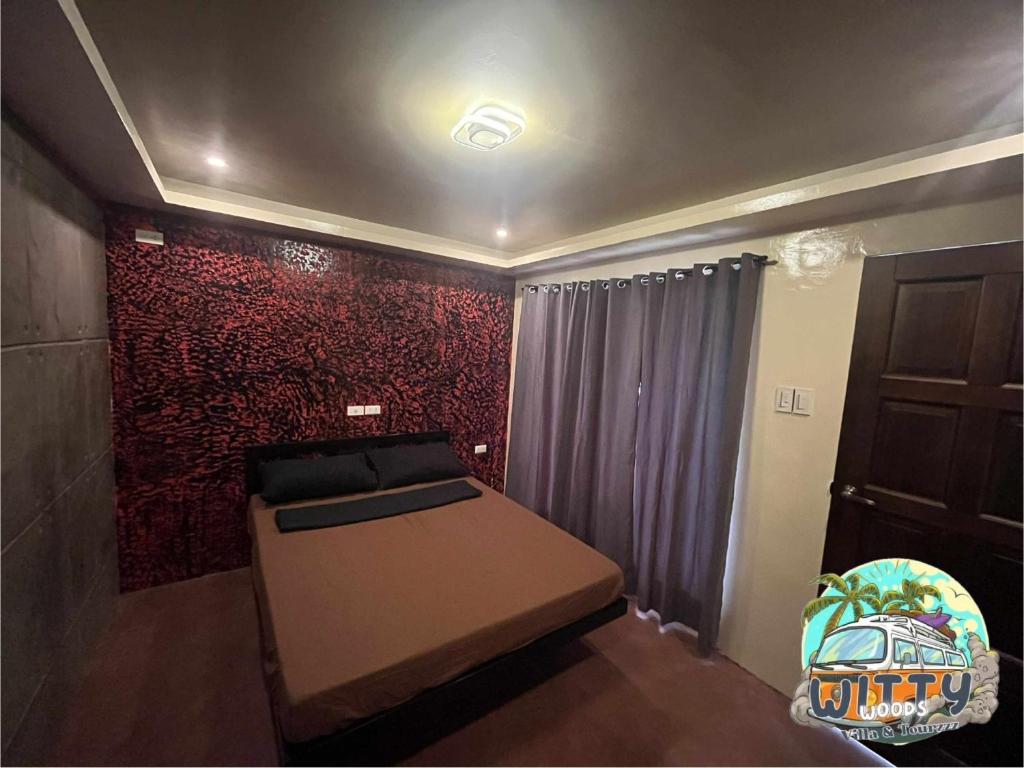 a room with a bed and a red wall at Witty Woods Guesthouse in Camalig