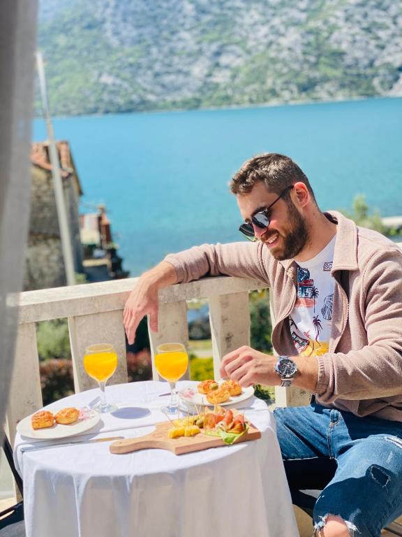 Ein Mann sitzt mit einem Teller Essen an einem Tisch. in der Unterkunft Villa Blanca - Risan in Risan