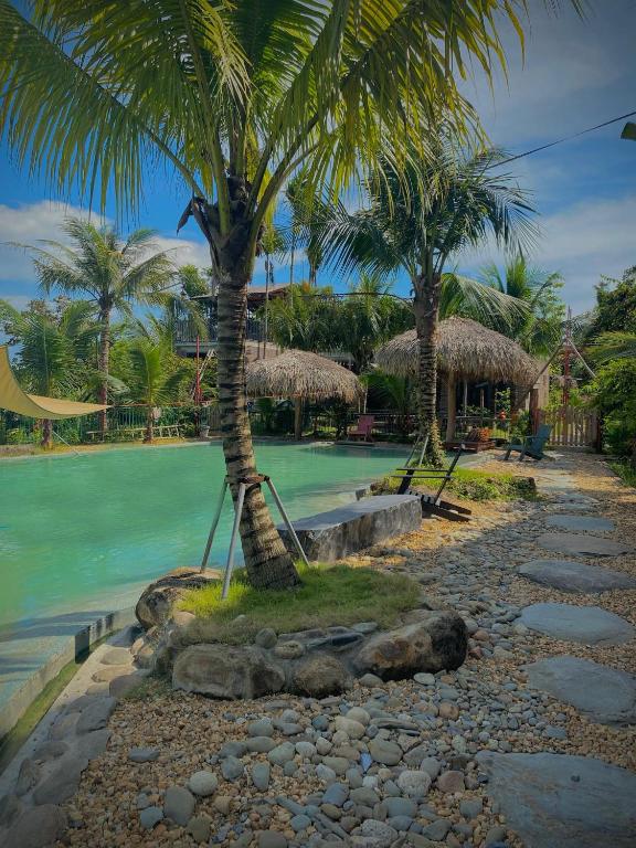 a resort with palm trees and a pool of water at Bird House Ecolodge Nghệ An in Hữu Biêt