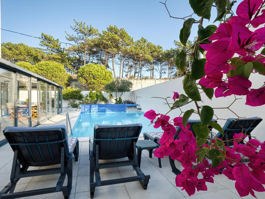 a patio with a table and chairs and pink flowers at Maresia Villa Mar in Nazaré