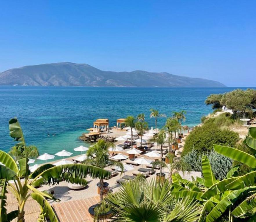 a beach with umbrellas and chairs and the ocean at KEAN Apartments in Vlorë