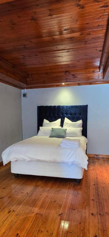 a bedroom with a white bed with a wooden ceiling at Relax Guest House in Goodwood