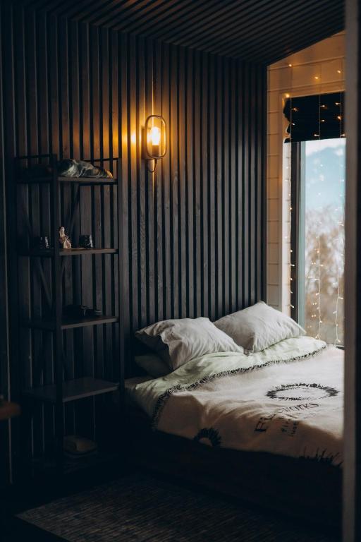 a bedroom with a bed with a window and a lamp at Putyscha house in Tukhlya