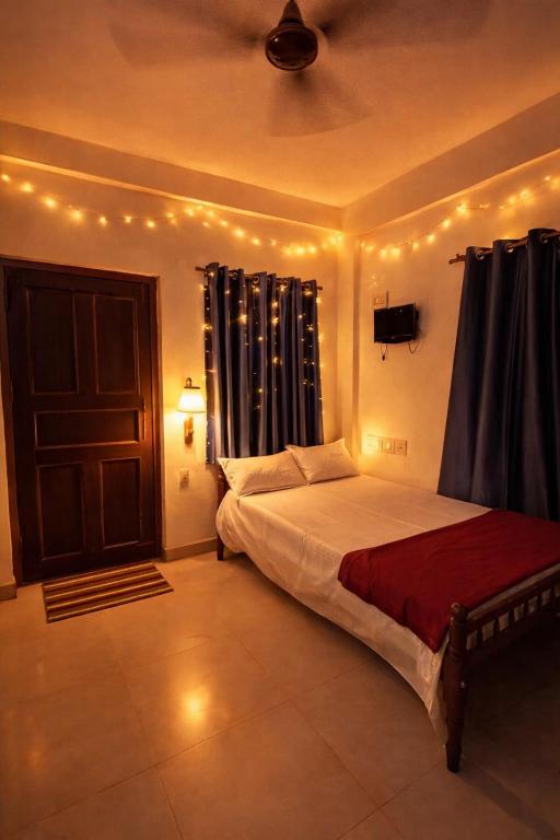 a bedroom with a bed and a door with curtains at G studio in Guruvāyūr