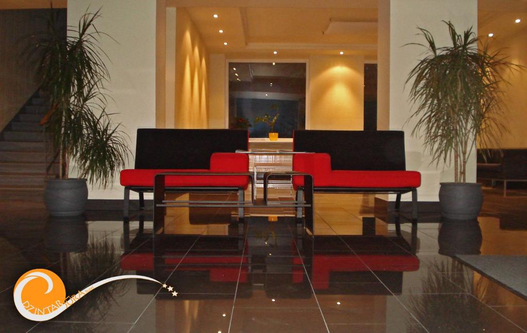 dwa czerwone krzesła i szklany stół w holu w obiekcie Dzintarjura w mieście Windawa