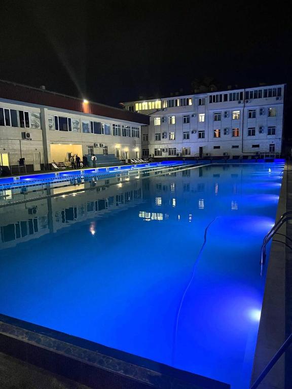 a large pool of blue water in front of buildings at Avenue Hotel Tashkent in Tashkent