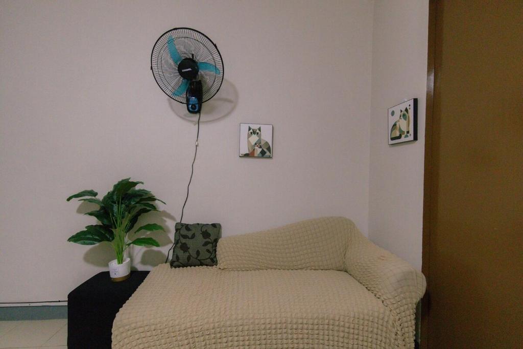 a living room with a couch and a fan at M&B Urban Haven in Suba