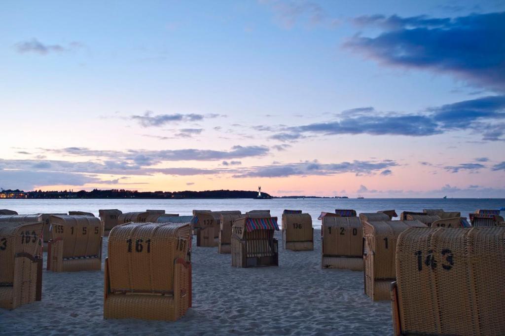 a beach with many beach chairs on the sand at StrandHotel Seeblick, Ostseebad Heikendorf in Heikendorf