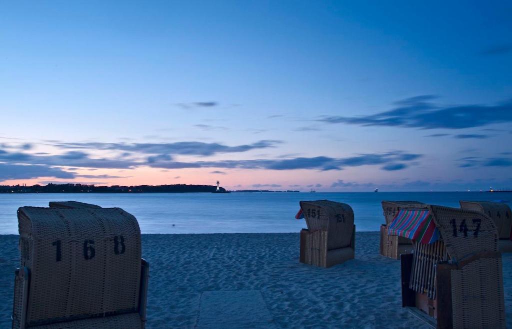 a group of chairs on the beach at dusk at StrandHotel Seeblick, Ostseebad Heikendorf in Heikendorf
