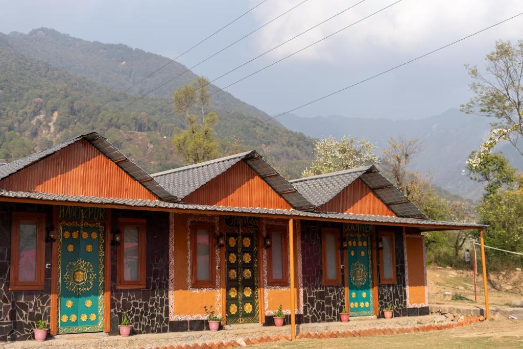 a small building with a mountain in the background at Mhara Himachal in Bīr