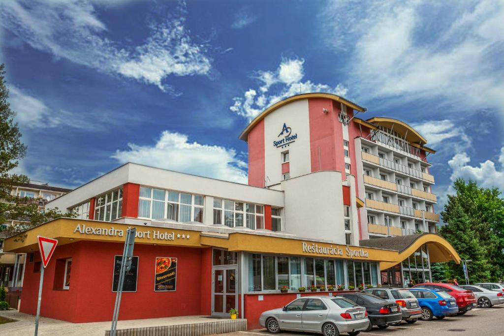 a large building with cars parked in front of it at Alexandra Šport Hotel in Púchov