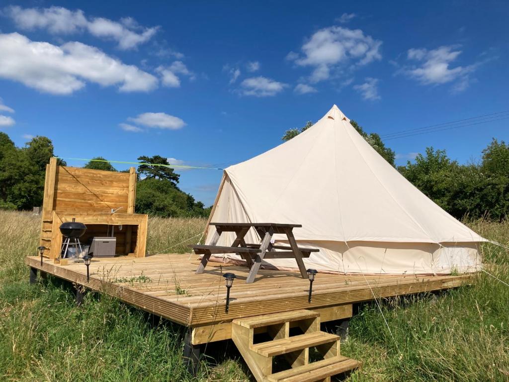 a white tent on a wooden platform in a field at Glamping Tent - Bell Tent in Brackley