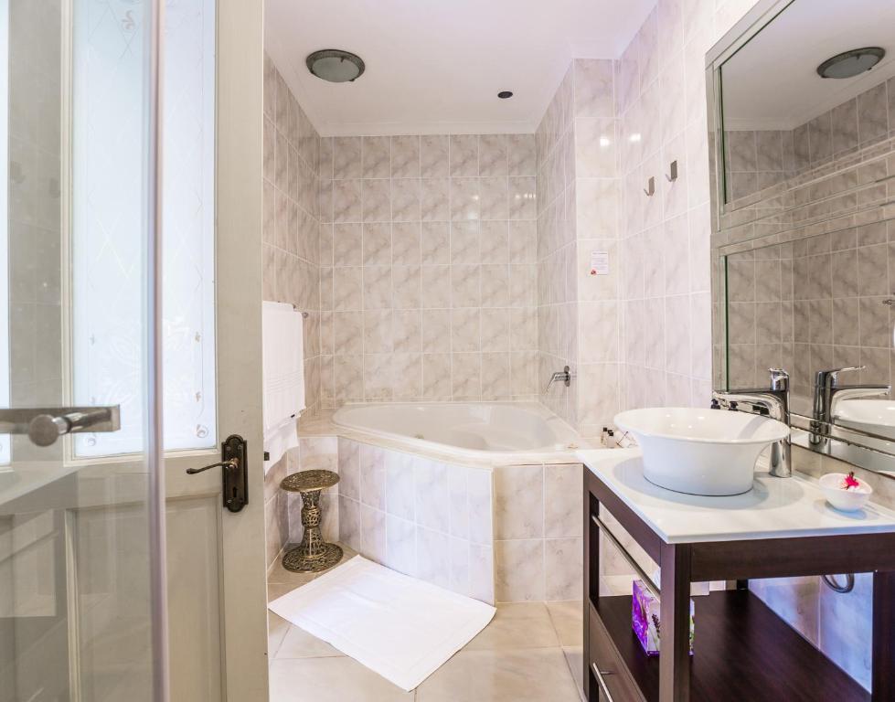 Hermanus Manor في هيرمانوس: حمام أبيض مع حوض استحمام ومغسلة