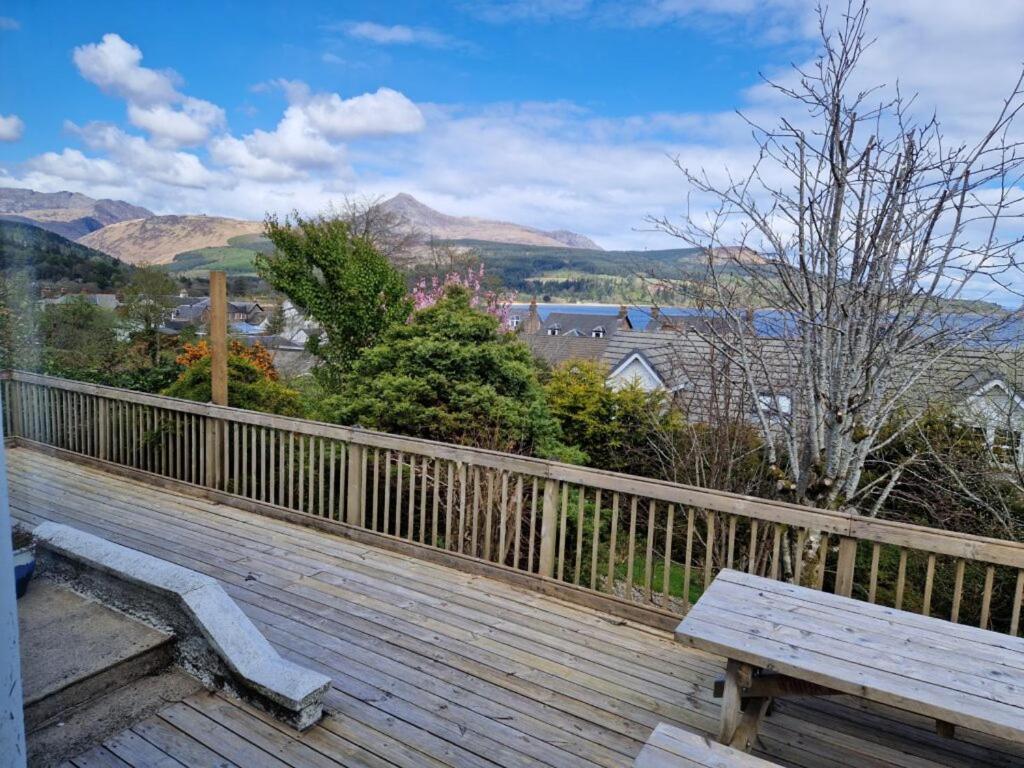a wooden deck with a bench on a balcony at Airlie Gardens in Brodick
