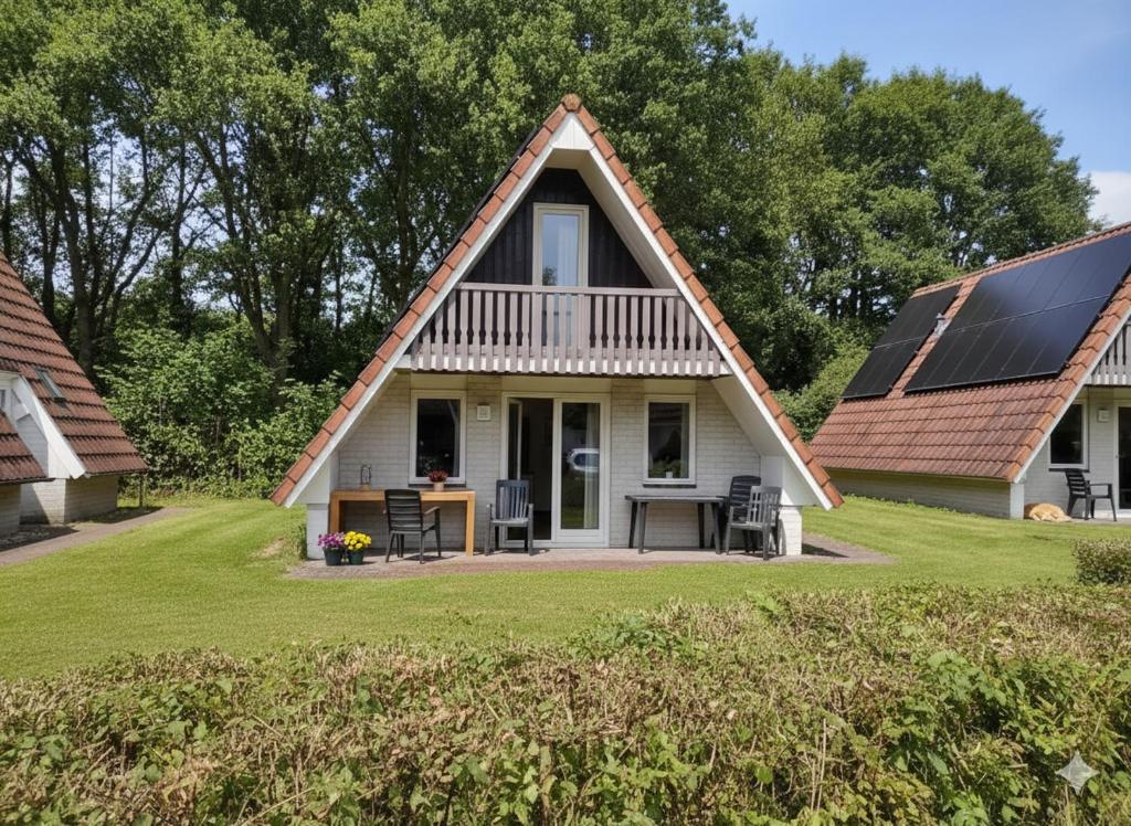 a cottage with a thatched roof with a table and chairs at De Eekhoorn in Gramsbergen