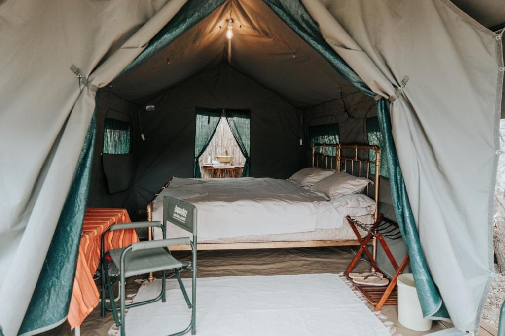 a bedroom in a tent with a bed and a chair at Bunduz Mara in Sekenani