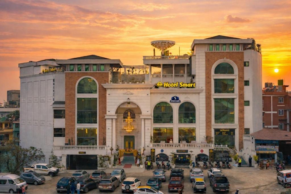 a building with a lot of cars parked in front of it at Hotel Smart Durbar in Dharampur
