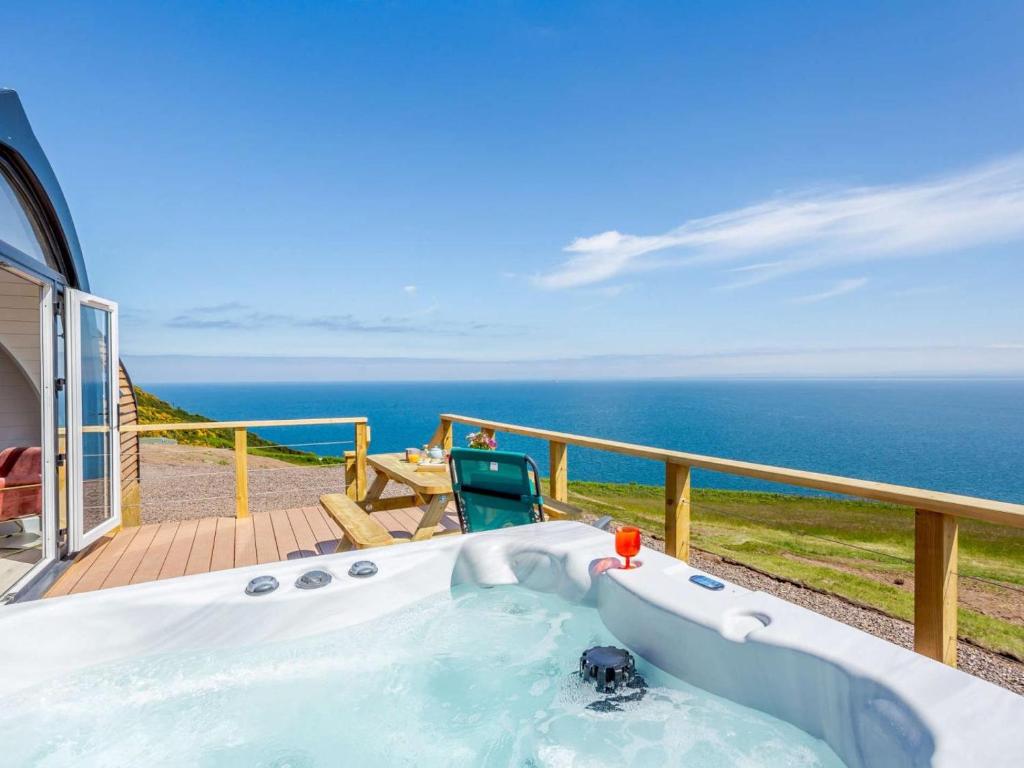 a hot tub on a deck with the ocean in the background at 1 Bed in Tain oc-81337 in Nigg
