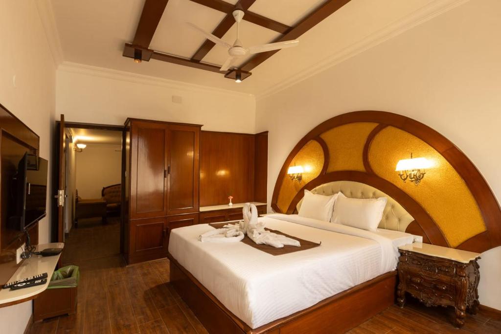 a bedroom with a large white bed with an arched headboard at Welbeck by The Beehives in Ooty