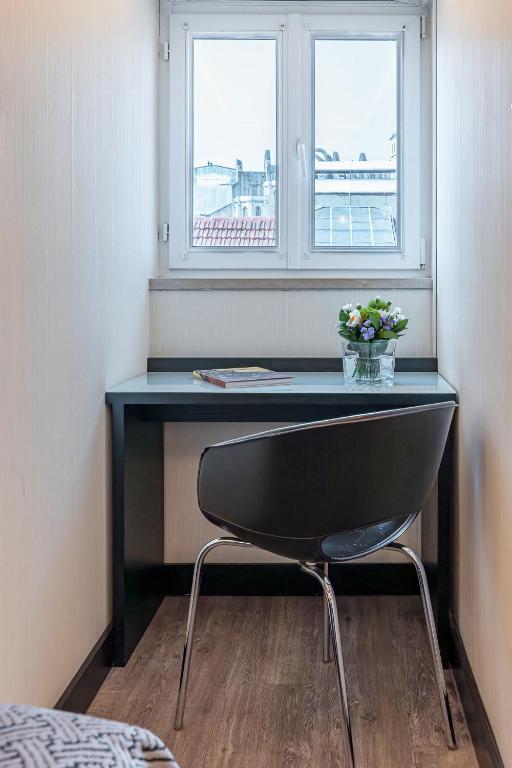A compact desk and chair fit into a narrow room beside a double window.