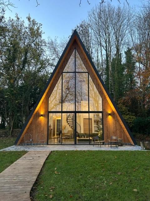 a large house with a large window in a park at Nordic Bath Lodge In Normandy in Donnay