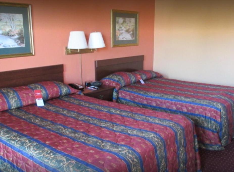2 Betten in einem Hotelzimmer mit roten Wänden in der Unterkunft Econo Lodge Lavonia in Lavonia